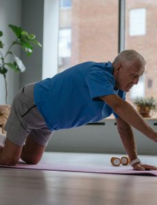 an elderly man exercising on a yoga mat